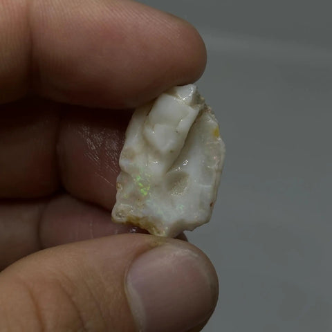 Hand holding raw opal cutting material from Coober Pedy multicolor barred opal stone light and dark for jewelry making and lapidary projects DIY friendly authentic Australian opal chips suitable for cabochon or bead work