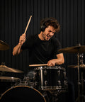 Drummer in headphones playing drums in front of Premium Soundproof Acoustic Panels For Home Studios And Home Offices.