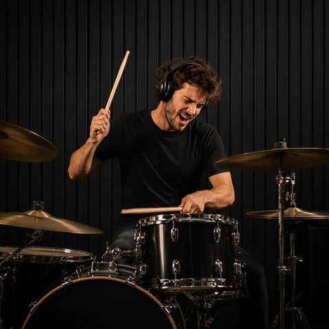 Drummer in headphones playing drums in front of Premium Soundproof Acoustic Panels For Home Studios And Home Offices.