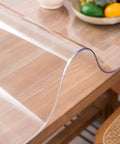 Clear Table Protector Mat 14 By 24 Inches, 1.5mm Thick Heavy Duty Desk Cover on a wooden dining table with fruit bowl.