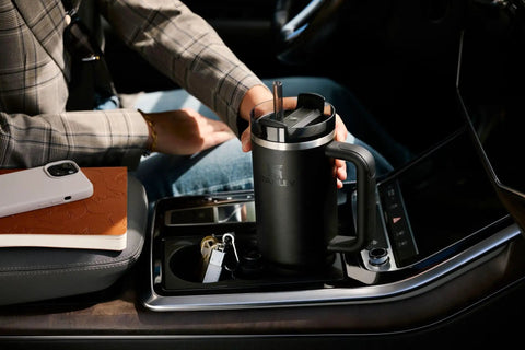 Person holding Quencher H2.0 Tumbler with Handle and Straw 40 oz for travel in a car cup holder