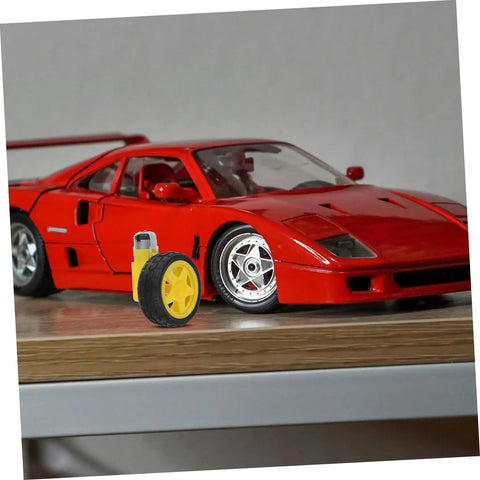 Electric Motor And Plastic Tire Wheel Set For RC Cars And Trucks next to a red model car on a wooden shelf
