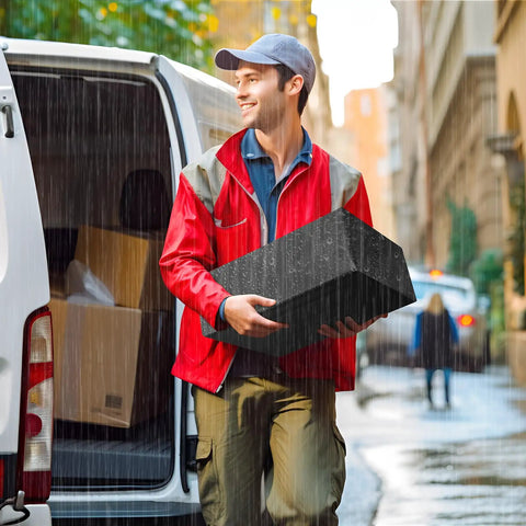 Delivery person holding black parcel in rain, showcasing the Self Seal Poly Mailers 14.5 X 19 Inch 100 Pack Tearproof Shipping Bags.