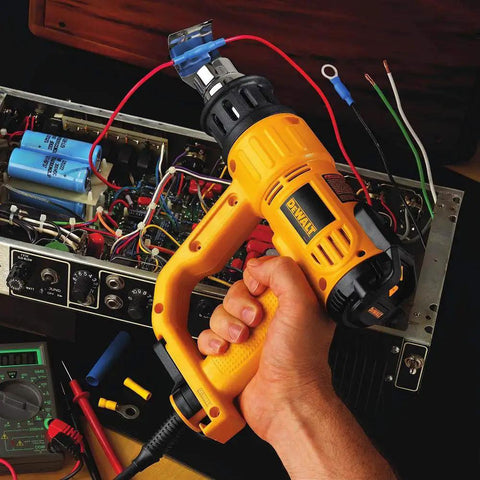 Holding a yellow Heat Gun With LCD Display And Accessory Kit For DIY Projects; used for electronics repair, shown in action.