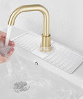 Clear Silicone Sink Splash Guard Mat 14.4 x 5.4 Inches in use with gold faucet, hands catching water