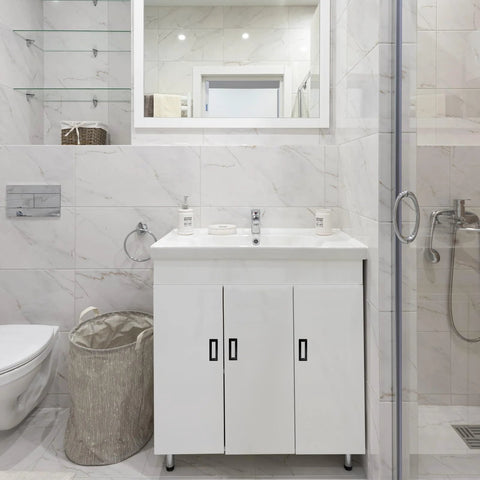 Modern bathroom with white cabinet, marble tiles, and glass shower enclosure