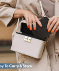 Person placing a heart-shaped item into a beige box-shaped bag, showing portability for Must Have Carry Along Portable Sewing Kit With Mixed Color Threads.