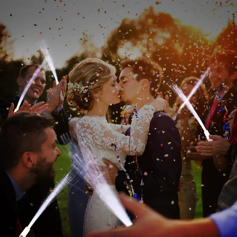 Wedding couple kissing surrounded by guests holding white fiber optic wands glow sticks light up LED sparklers for weddings and parties
