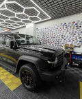 Black SUV under Ultra Bright Led Garage Lights With Hexagonal Grid System For Large Garage Or Workshop 6500K Daylight Color IP54 Rated