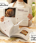 Person holding open book from All In One Sourdough Starter Kit With Pot 34 Oz Starter Jar 4 Banneton Baskets Scraper Scale Kit