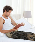 Stylish Steampunk Industrial Aged Human Heart Rusty Metal Gears Pajama Pants Lightweight Sleep Lounge Bottoms With Pockets And Button Fly For Men And Women Medium worn by a man reading in bed.
