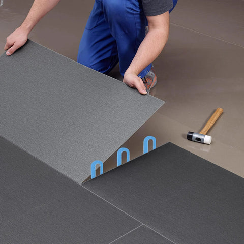 Three blue plastic horseshoe tile shims (U-shaped) for leveling ceramic floor tiles.