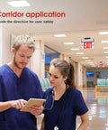Corridor with Red LED Edge Lit Exit Sign With Battery Back-Up, Brushed Aluminum Housing, two medical professionals in blue scrubs