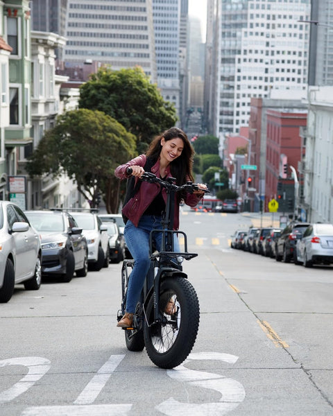 Electric bike with hydraulic disc brakes; side view of a black fat-tire bike ridden on an urban street.