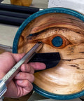 Unhanded 12-inch stainless steel 90° carbide woodturning tool held near a turned wooden bowl with blue rim.