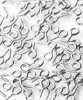 Mini Silver Metal Hoop Eye Pin Screws For DIY Jewelry Making And Craft Projects, Cork Bottle Charms And Tiny Pendant Suspensions, 12mm By 5mm, 100 Pieces, Great For Earrings And Delicate Bead Charms. Silver screw eye pins scattered on white background.