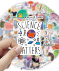 Hand holding sticker from 100 Piece Science Stickers Pack For Chemistry Biology Physics Nerds showing planet and science icons.