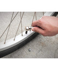 Hand using tire chuck from Air Tank Repair Kit With Safety Valve, 0 To 200 Psi Pressure Gauge, 4 Ft Air Hose With Tire Chuck, Heavy Duty Manifold, Model W10058 for inflating bike tire.