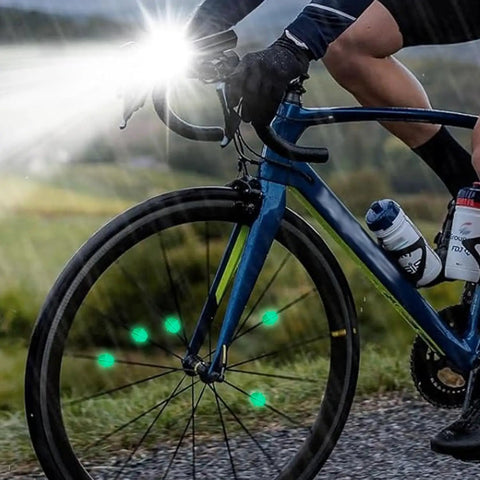 Cyclist on road bike with 36 Pack Glow In The Dark Luminous Bicycle Wheel Spoke Wrap Tubes In Colorful Plastic glowing at dusk.