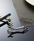 Gold and silver stainless steel deer-shaped utensil holders on a reflective black surface