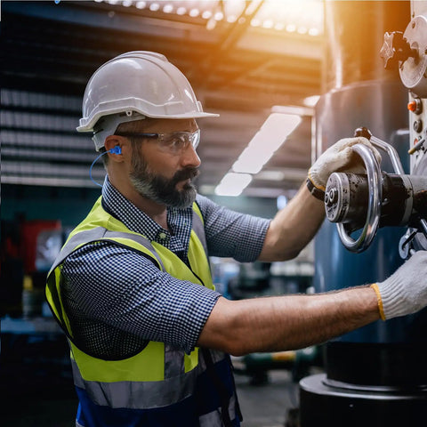 Worker wearing Noise Cancelling Ear Plugs 27dB NRR, Corded And Reusable, Individually Packaged With Belt Clip, at work station.
