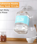 Heavy Duty Adhesive Hooks 12 Pack Holds Up To 13 Lbs Each Waterproof No Nail Wall Hangers displaying 13 lb jug in kitchen