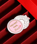 Cute Pink Golf Ball Marker Hat Clip For Women Gals Golf Accessory on textured surface with inspirational message