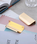 10 Pack Brushed Gold Edge Finger Cabinet Pulls 3.15 Inch Aluminum Drawer Handles on a desk with books and papers