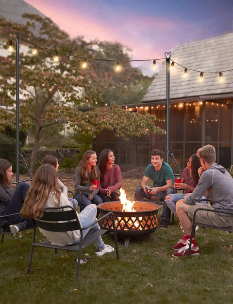 Group enjoying evening under Two Pack 9.8 Ft Outdoor String Light Poles For Hanging Lights Durable Weather Resistant Yard Backyard Garden Patio Deck Lighting Stand Perfect For Outdoor Parties Weddings And Lit Backyard Vibes.