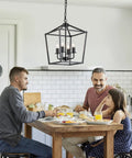 Family enjoying breakfast under Four Light Farmhouse Industrial Lantern Cage Pendant Light In Gun Black Finish For Kitchen Island Dining Room Hallway Entryway And Foyer UL Listed Retro Rustic Vibe Easy To Install.