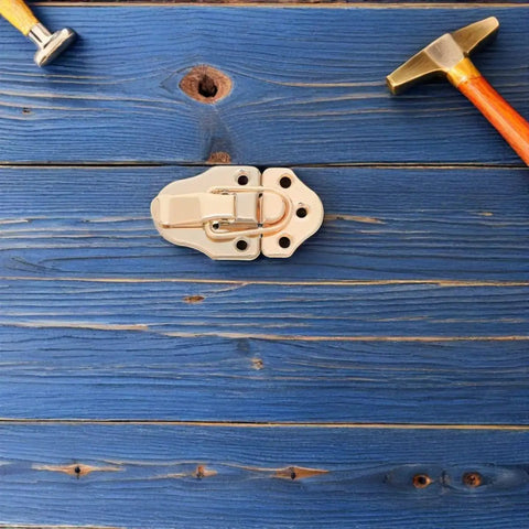 Six Golden Metal Toggle Latches For Vintage Wood Boxes Tool Cases And Suitcases on blue wooden surface with hammer.