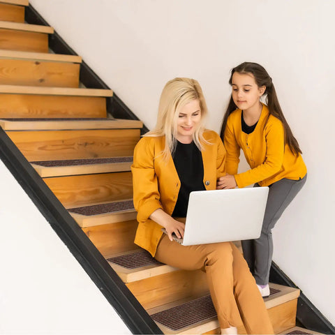 Woman and child sitting on wooden steps with No Slip Stair Treads 8 By 30 Inches 15 Pack With Pre Applied Adhesive Indoor Stair Carpet Runners
