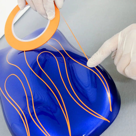 Applying Pro Grade Fine Line Tape Half Inch Orange Masking Tape For Precise Paint Edges And Auto Detailing on blue surface
