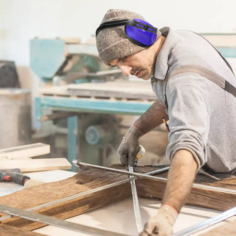 Man wearing Six Pack Adjustable Safety Ear Muffs For Noise Reduction And Hearing Protection All Day Comfort For Hunting Shooting Construction And Woodworking Blue while working in a woodworking shop.
