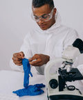 Blue nitrile disposable gloves being donned by researcher at lab beside a microscope