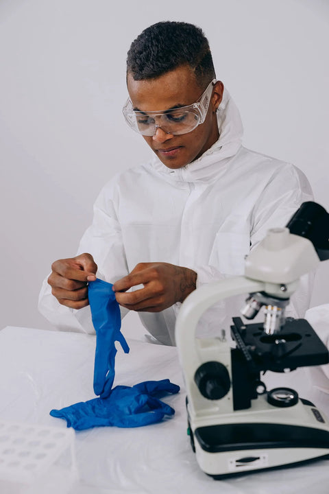 Blue nitrile disposable gloves being donned by researcher at lab beside a microscope