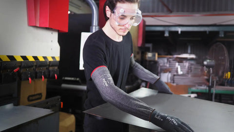 Heavy Duty Cut Resistant Arm Sleeves Slate Grey 50 Pack snug thumb slot worn while handling materials in a workshop.