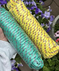 Two rolls of multicolor yellow and green polypropylene rope held in hand; part of 4 Pack 50 Feet Each Three Eighths Inch Polypropylene Rope Heavy Duty All Purpose Utility Line Weather Resistant Tie Downs For Camping, Fishing, Pulling And Outdoor Use Multicolor Red Yellow Blue Green.