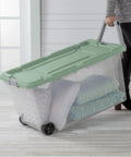 Heavy Duty Rolling Storage Bins, 40 Gallon Capacity, 2 Pack Garage Organization Cart With Wheels, Hella Tough Mobile Container For Moving Supplies, Workshop Tools, And Camping Gear, Green Sage with pillows and blankets.