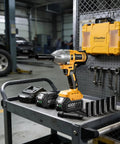 Half Inch Cordless Impact Wrench With Brushless Motor 1032 Foot Pounds Beefy Torque 1400 Newton Meters Electric Impact Driver Kit With 2X 4Ah Batteries LED Light Charger Six Sockets And Three Speed Settings For Car Truck Mower on a workbench in a garage setting.