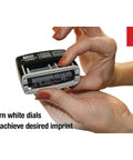 Close-up of hands adjusting white dials on Slick Self Inking Micro Message Dater Stamp With Quick Flip Phrases for precise imprint.