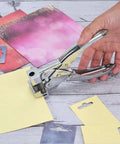 Hand using Heavy Duty T Slot Hole Punch Handheld Tool for ID cards, punching hole in yellow cardstock, silver zinc alloy, spring action.