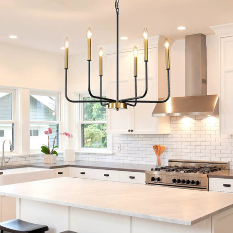 Farmhouse Six Light Chandelier in black and gold hanging over kitchen island in modern kitchen with white cabinetry.
