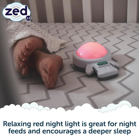 Calming Baby Sleep Aid With 6 Soothing Vibration Modes And Red Night Light next to baby feet on a crib mattress.