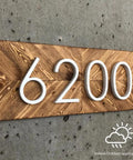 Wooden sign with number 6200 in white raised letters mounted on concrete wall for indoor or outdoor use.