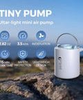 Tiny Ultra Mini Portable Air Pump For Inflatables on rock showing features like 2.82 oz size, lightweight design, inflate and deflate