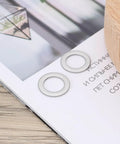 30Pcs Flat Washers 304 Stainless Steel 10x16x1mm Door Hinge Gaskets on a wooden table with a magazine