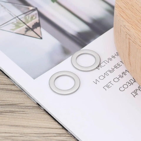 30Pcs Flat Washers 304 Stainless Steel 10x16x1mm Door Hinge Gaskets on a wooden table with a magazine