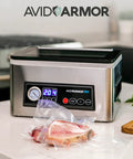 Front view of Avid Armor chamber vacuum sealer stainless steel with 11.5-in seal bar and digital controls, meat in bag