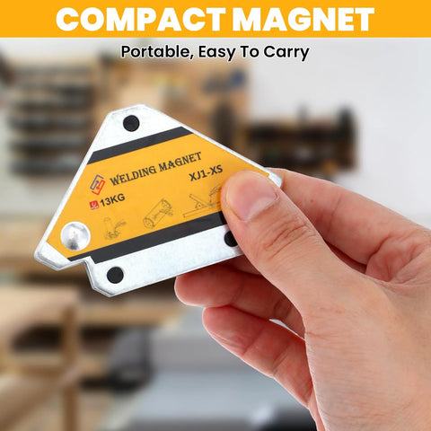 Compact welding magnet held in hand; metal body with yellow label showing 13KG and XJ1-XS